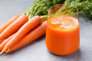 Carrot juice in glass and fresh carrots